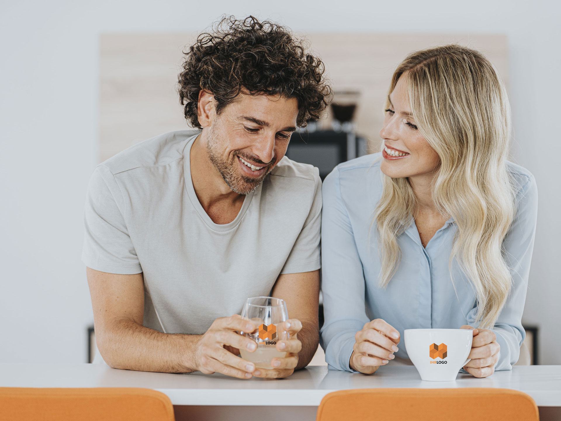 Pärchen trinkt Wasser und Kaffee aus Geschirr mit identischem Logo